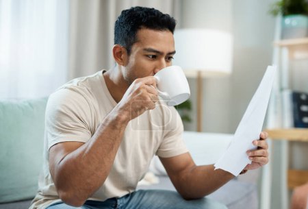 Photo for Asian man, documents and drinking coffee in finance, expenses or checking bills on living room sofa at home. Male person with paperwork, latte or cup of tea and reading contract or insurance at house. - Royalty Free Image