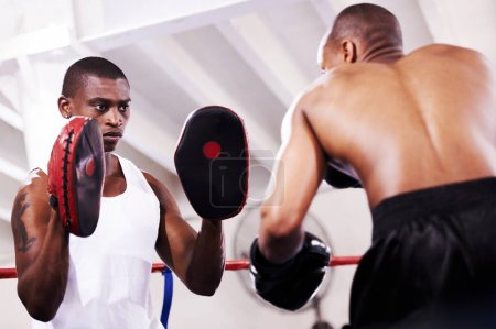 Téléchargez les photos : Homme noir, boxeur et entraîneur personnel en légitime défense ou combat d'anneau à l'entraînement de gymnase, l'exercice ou l'entraînement ensemble. Homme africain avec partenaire de boxe ou d'épargne se préparant pour la compétition sportive. - en image libre de droit