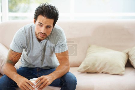 Photo for Depression, thinking and sad man on a sofa with stress, anxiety or broken heart at home. Fail, crisis or male person in living room overthinking, disaster or lonely, worried or disappointed in house. - Royalty Free Image