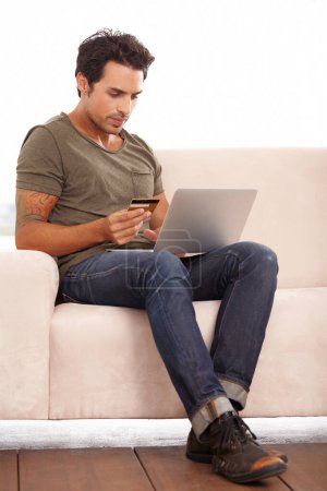 Photo for Credit card, laptop and man on sofa for online shopping, e commerce and digital payment on fintech software. Person on couch, typing on computer and internet banking for financial investment or sale. - Royalty Free Image