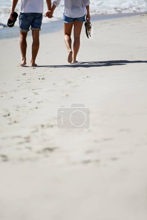 Photo for Love, holding hands and legs of couple on beach for date, outdoor bonding and tropical holiday. Romance, man and woman from back, walk and relax on vacation together with travel, care and adventure - Royalty Free Image