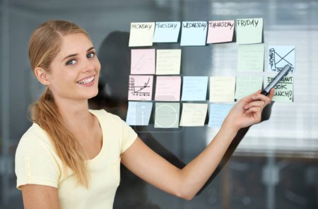 Photo for Woman, pointing and sticky notes on glass wall, graph and smile for seminar, creative and portrait. Presentation, strategy and office job for weekly schedule, workplace and financial audit report. - Royalty Free Image