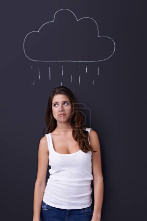 Photo for Thinking, sad and rain cloud with woman on a chalkboard for drawing, emotion or expression in studio. Depression, idea or weather and an unhappy young person with a chalk picture of a winter storm. - Royalty Free Image