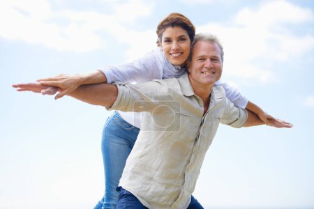 Photo for Mature couple, portrait and piggy back on vacation, airplane hands and happiness in blue skies. Man, woman and bonding together with smile, marriage and commitment with affection, holiday and joyful. - Royalty Free Image