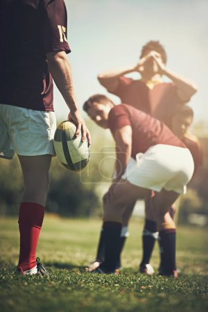 Foto de Rugby, hombres de inicio y fitness con pelota en un campo con grupo, scrum y pitch, entrenamiento y potencia al aire libre. Equipo de energía, balonmano y deportes en un parque para la competición, la acción o el desafío de rendimiento. - Imagen libre de derechos