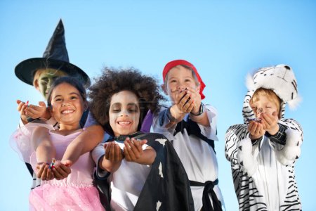 Téléchargez les photos : Enfants, groupe et les mains en costume d'Halloween pour bonbons sucrés demandant, tour ou régal pour fantaisie. Amis, sourire et s'habiller en sorcière ou pirate pour le plaisir des vacances, le développement des enfants sur fond de ciel. - en image libre de droit