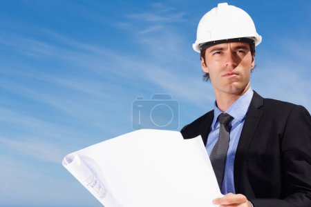Photo for Industry, blueprint and construction worker thinking by blue sky on building rooftop for planning. Engineering, professional and male industrial employee with architecture drawing for project - Royalty Free Image