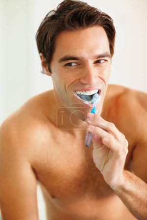 Photo for Bathroom, brushing teeth and man with oral hygiene, wellness and grooming routine for fresh breath. Person, home or guy with toothbrush, cleaning his mouth and morning with dental health or self care. - Royalty Free Image