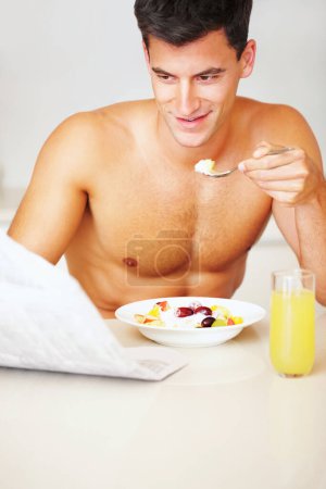 Téléchargez les photos : Heureux, mangeant et jeune homme avec salade de fruits à sa maison pour un petit déjeuner sain ou une collation. Sourire, bien-être et homme du Canada dégustant du yaourt pour le repas dans la cuisine de son appartement moderne - en image libre de droit