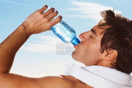 Photo for Young man, drinking water bottle or towel for workout with health body, fitness and vacation. Model, thirsty or natural glow with h2o drink for hydration or post cardio exercise by sky background. - Royalty Free Image