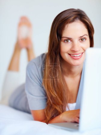 Photo for Home, portrait and woman with a laptop, relax and connection with happiness, network and smile. Face, person and girl with a computer, internet and website information with technology and bedroom. - Royalty Free Image