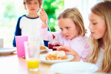 Photo for Breakfast, jam spread and child in morning, weekend and siblings for nutrition, orange juice and donut. Brother, sisters and enjoying food together for hunger, health and energy for good day. - Royalty Free Image