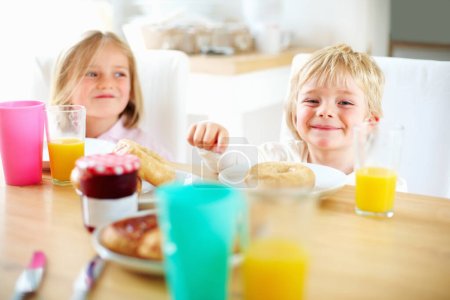 Photo for Smile, kitchen and children eating breakfast together for healthy, wellness and diet meal. Happy, laughing and kid siblings bonding and enjoying lunch or brunch with juice at table in family home - Royalty Free Image