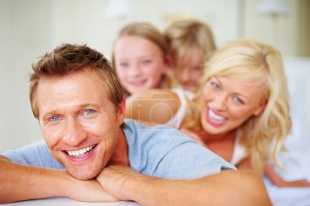 Photo for Portrait, funny and a family lying on a bed together while in their home on a weekend morning. Face, love and father, mother and children laughing in the bedroom of an apartment to relax for bonding. - Royalty Free Image