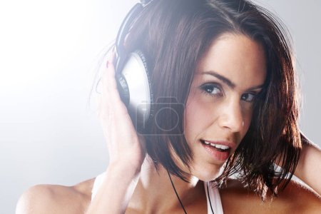 Photo for Headphones, woman and portrait with music, audio and online radio with confidence in studio. White background, female person and podcast with dancing and smile from break and listening to sound. - Royalty Free Image