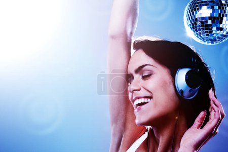 Photo for Closeup, happy woman and headphones for music in studio on blue background, lens flare and mockup for disco. Female model, eyes closed and energy for song, movement and freedom with smile for dance. - Royalty Free Image
