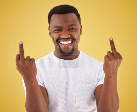 Photo for Happy, middle finger and portrait of black man in studio with rude, insulting and bad sign. Emoji, symbol and face of person with hand gesture on yellow background for joke, rebel attitude and laugh. - Royalty Free Image