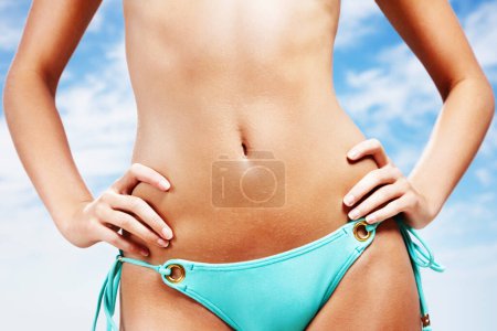 Photo for Woman, stomach and bikini in summer, blue sky background or freedom for mockup space, holiday or cloud. Girl, hands and swimwear with abdomen, vacation and outdoor in sunshine for wellness in Spain. - Royalty Free Image