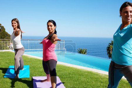 Photo for Stretching, yoga and friends on grass for fitness, exercise and holistic workout for healthy body outdoors. Pilates, happy and women on mat by ocean or pool for wellness, balance and flexibility. - Royalty Free Image