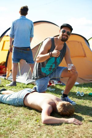 Photo for Sleeping, drunk or friends on grass in festival hangover in a social celebration or party or concert. Portrait, thumbs up or happy people drinking alcohol on outdoor music event or holiday vacation. - Royalty Free Image