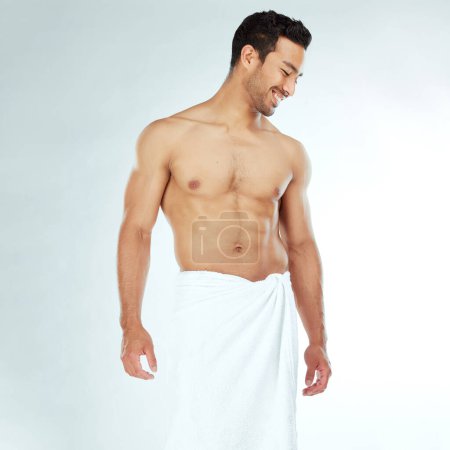 Photo for Shower, towel and happy fitness man in studio for wellness, hygiene or body care routine on white background. Cleaning, grooming or muscular Japanese male model with pamper, cosmetics or treatment. - Royalty Free Image