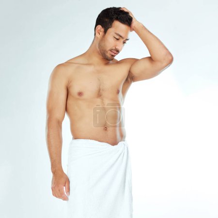 Photo for Towel, shower and fitness man thinking in studio for wellness, hygiene or body care routine on white background. Cleaning, grooming or muscular Japanese male model with pamper, cosmetics or treatment. - Royalty Free Image