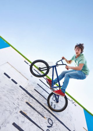 Foto de Bicicleta, truco y adolescente en el aire en skatepark con energía en el rendimiento para la competencia o evento en verano. Bicicleta, salto o truco en la pared con puntuación, tabla y la libertad intrépida de ciclista en el cielo. - Imagen libre de derechos