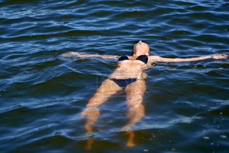 Photo for Ocean, water and woman floating in bikini with peace and freedom in summer, holiday or vacation. Person, relax and calm swimming in sea, lake or pool with swimwear, costume and waves offshore. - Royalty Free Image