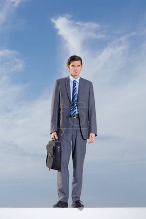 Photo for Portrait, briefcase and a business man on a blue sky background for International travel or a journey. Corporate, work and a confident young professional employee outdoor during summer for a trip. - Royalty Free Image