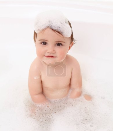 Photo for Baby in bath with soap, water and portrait of clean fun in for skincare, wellness and hygiene. Bubbles in bathtub, foam and child in bathroom with cute face, care and washing dirt, germs and smile - Royalty Free Image