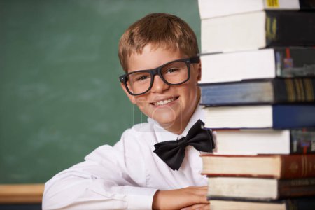 Photo for Boy student, smile and portrait with books, classroom and learning for exam, assessment and studying for knowledge. Child, notebook and happy for education, development and glasses by chalkboard. - Royalty Free Image