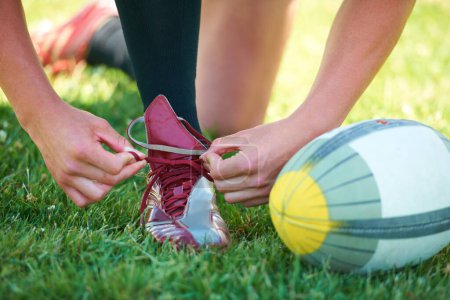 Téléchargez les photos : Rugby, ballon et sport avec des chaussures de personne sur le terrain pour l'entraînement, la pratique et le défi. Santé, début et jeux avec gros plan de lacets d'athlète sur le terrain extérieur pour le stade et la forme physique. - en image libre de droit