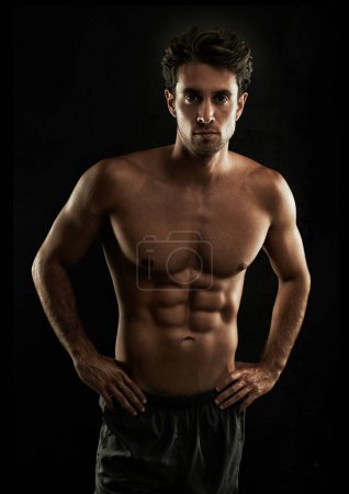 Photo for Confident, black background or portrait of man with six pack, strong abs or stomach in studio for fitness. Cool, model or ripped person with healthy body, dark shadow or abdomen muscle for wellness. - Royalty Free Image