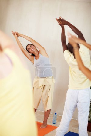 Photo for Stretching, yoga and happy personal trainer with class for fitness, exercise and workout on mat. Pilates, club and instructor with men and women for wellness, balance and flexibility for healthy body. - Royalty Free Image