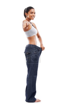 Téléchargez les photos : Femme heureuse, portrait et pointage pour perdre du poids en jeans ou décision sur fond de studio blanc. Slim femme ou modèle sourire pour choisir dans la santé et le bien-être sur l'espace de maquette. - en image libre de droit
