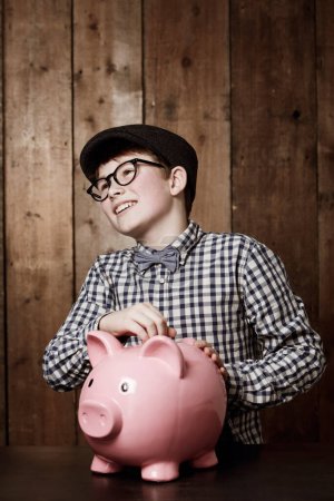 Photo for Piggy bank, money and boy child with savings, growth or investment, planning or learning at home. Happy, budget and kid in a house with coin, container or cash box for future, financial and security. - Royalty Free Image