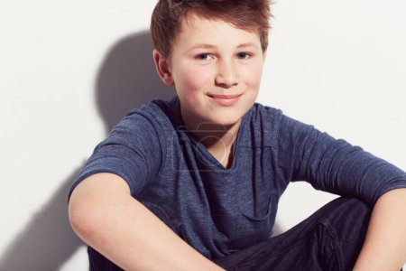 Photo for Happy, teenager and portrait of boy with fashion sitting in white background of studio. Cool, style and kid with a smile, confidence and pride in trendy outfit or relax in clothes on backdrop. - Royalty Free Image