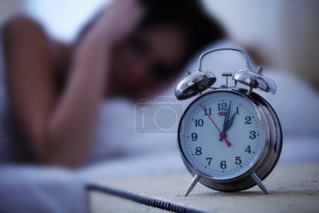 Téléchargez les photos : Réveil, réveil et femme frustrée dans un lit avec les mains sur les oreilles pour le bruit, le son ou l'alerte à la maison. Temps, cloche et femme dans une chambre flou avec fatigue, épuisement professionnel ou sommeil tardif de l'insomnie. - en image libre de droit