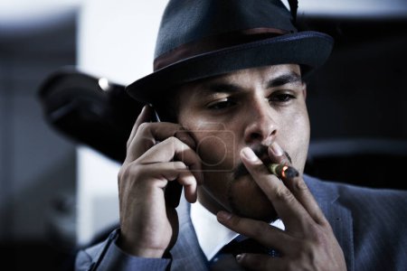 Photo for Gangster, phone call and mafia for danger crime planning ransom, abduction or interrogation terror. Male person, cigar smoking and mobile device for hitman threat conversation, robbery or violence. - Royalty Free Image