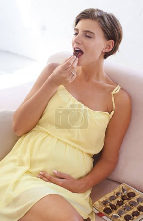 Photo for Happy woman, eating chocolate and pregnant in home, alone and enjoying delicious pregnancy craving. Good mood, comfort food and candy dessert for maternity, snack and sweet tooth satisfaction. - Royalty Free Image
