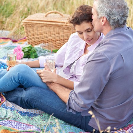 Photo for Kiss, senior couple and picnic in park, grass and basket in nature for a date or celebration with love and care. Mature, woman and man in field in summer, holiday or vacation with wine or drinks. - Royalty Free Image