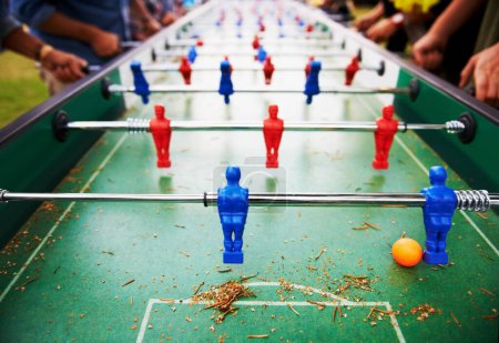 Photo for Playing, foosball and people outdoor with table, game or closeup on competition with ping pong ball. Soccer, board and small plastic football players or toys for social, event or sport at pub for fun. - Royalty Free Image