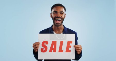 Photo for Excited man, portrait and sale sign for advertising, deal or discount against a blue studio background. Happy male person showing billboard or poster for marketing, promotion or special on mockup. - Royalty Free Image
