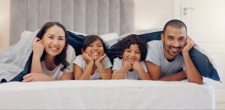 Photo for Portrait, smile and children with parents in bed relaxing and bonding together at family home. Happy, fun and young mother and father laying and resting with kids in bedroom of modern house - Royalty Free Image