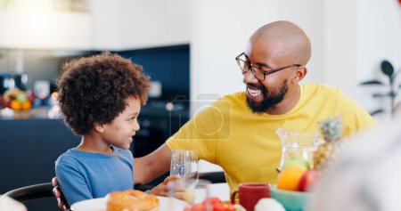 Photo for Black family, food and father with child for breakfast, lunch and eating together in home. Happy, talking and dad and boy at table for bonding with meal for health, nutrition and hunger in house. - Royalty Free Image