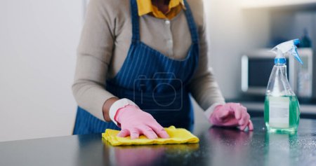 Téléchargez les photos : Femme, mains et table de nettoyage dans la cuisine pour l'entretien ménager, l'hygiène ou la surface sanitaire à la maison. Gros plan d'une femme, d'une femme de ménage ou d'un nettoyant essuyant des meubles pour la désinfection, l'élimination de germes ou de bactéries. - en image libre de droit