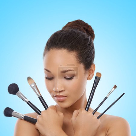 Photo for Woman, grooming and makeup brushes for cosmetics in studio, choice and decision for beauty. Female model person, tools and equipment for application, skincare and facial treatment by blue background. - Royalty Free Image