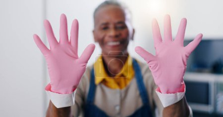 Téléchargez les photos : Mains, hygiène et gants pour le nettoyage avec une femme de ménage dans la cuisine de la maison à la maison d'hôtes de l'hospitalité. Sécurité, service et caoutchouc rose ou latex avec nettoyant dans l'appartement pour les tâches ménagères. - en image libre de droit