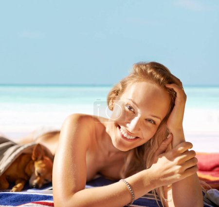 Téléchargez les photos : Femme, portrait et heureux sur la plage et bronzage avec chien, vacances et voyage à Hawaï. Femme, reposant et bronzant sur le sable et paisible par l'eau, la nature et le bien-être par l'océan et les animaux. - en image libre de droit
