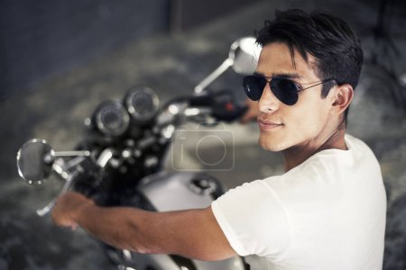 Photo for Handsome man, portrait and sunglasses on motorcycle for cool transportation or small vehicle in garage. Face of young male person or biker smile for automobile or ownership on mechanical motorbike. - Royalty Free Image